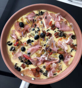 Raw Parma Ham & Mediterranean Vegetable Frittata cooking in a frying pan