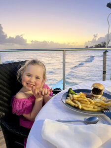 Girl eating dinner by the sea at Champers in Barbados