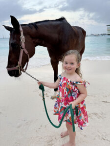 Girl holding horse's reins on a beach in Barbados